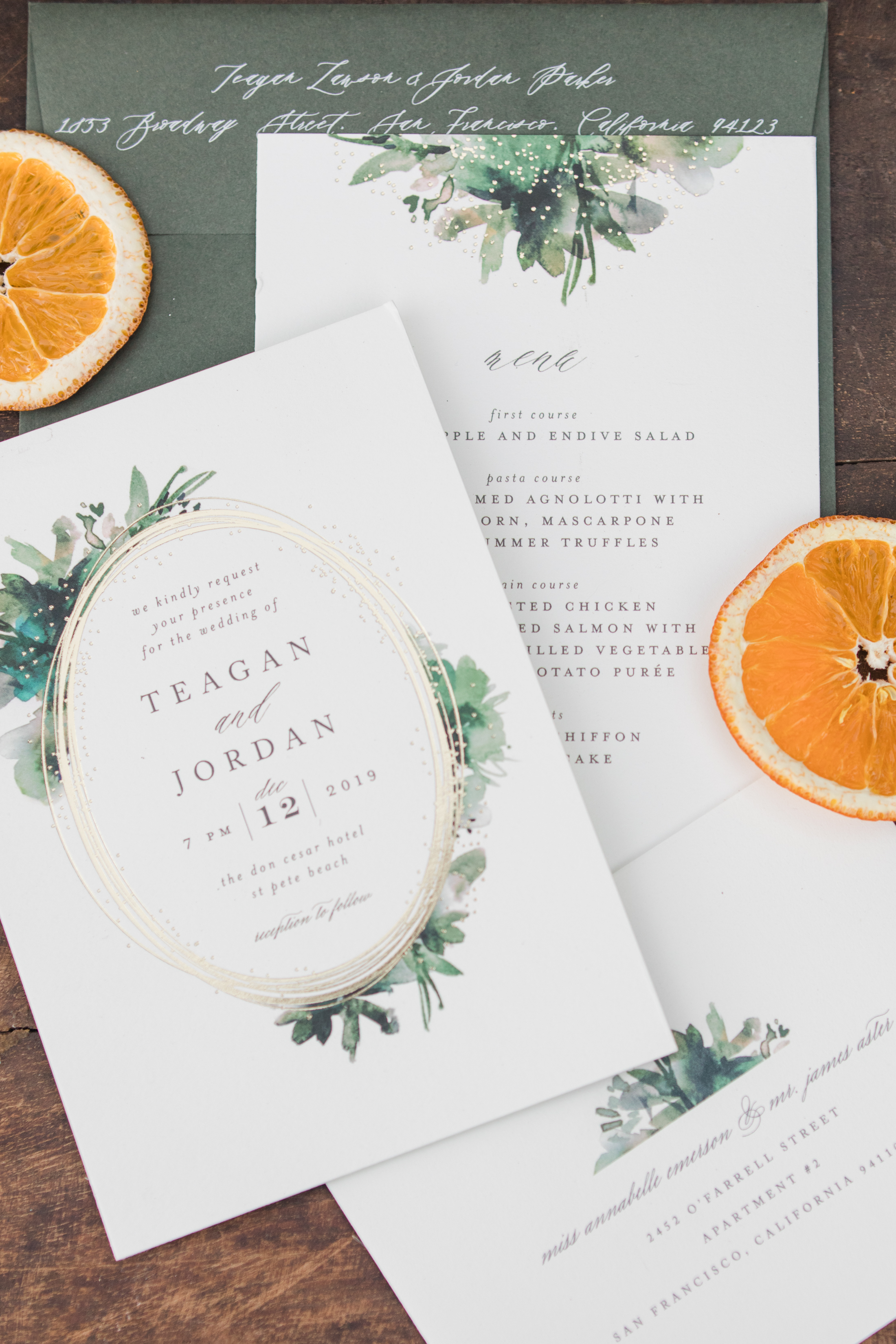 A green and white wedding invitation suite with dried orange slices